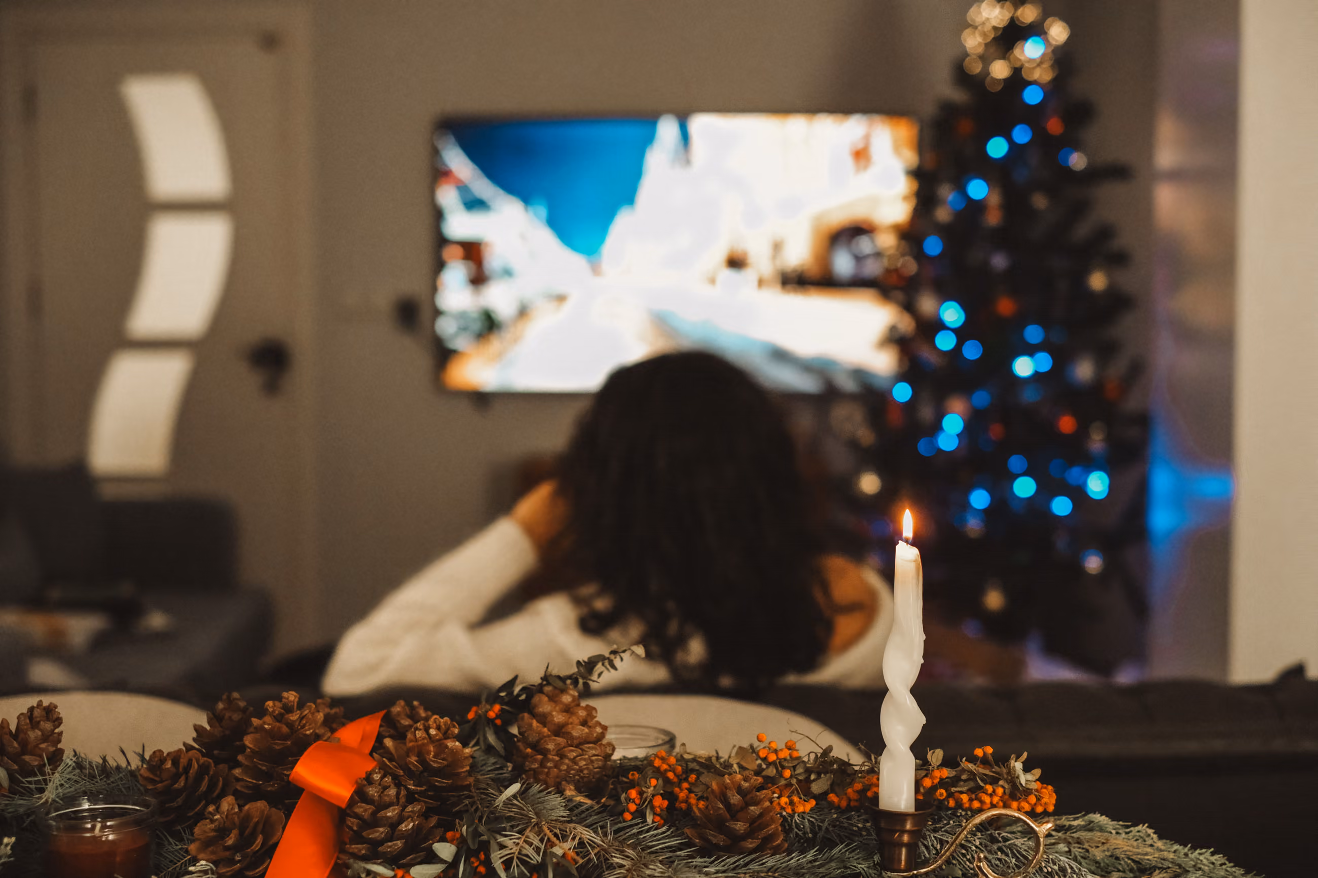 Settled on the sofa watching Christmas television beside a lit tree — UK Christmas TV abroad